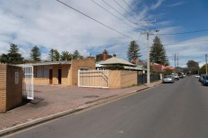 an empty street with a house and a fence at Glenelg Motel in Adelaide