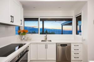 a kitchen with white cabinets and a large window at Martha's Maison Heated Spa & Unbeatable Bay Views in Safety Beach