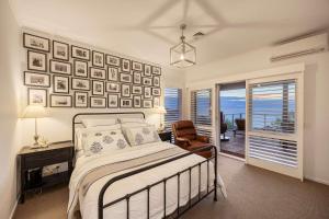 a bedroom with a bed and a desk and a window at Martha's Maison Heated Spa & Unbeatable Bay Views in Safety Beach
