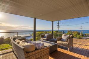 a patio with chairs and a couch on a deck at Martha's Maison Heated Spa & Unbeatable Bay Views in Safety Beach +29 photos