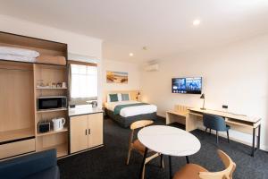 a hotel room with a bed and a desk at Glenelg Motel in Adelaide
