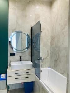 un baño con lavabo y espejo en Современные, светлые и уютные апартаменты в центре Астаны, en Astana