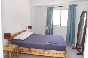 a bedroom with a bed with a blue blanket and a window at T3 Mindelo in Mindelo