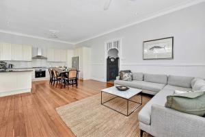 MerewetherにあるTosca Elegant Merewether Beach House with Poolのソファとテーブルとキッチンのあるリビングルーム