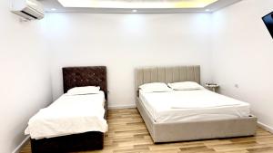 Habitación con 2 camas, paredes blancas y suelo de madera. en The Central Spot, en Tirana