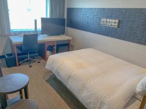a bedroom with a bed and a desk with a computer at Richmond Hotel Tokyo Musashino in Musashino
