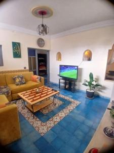 a living room with a couch and a flat screen tv at Dar Mobarak in Oualidia
