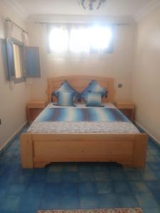 a bedroom with a large wooden bed with blue pillows at Dar Mobarak in Oualidia
