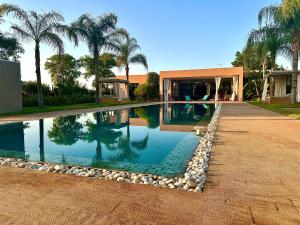 a swimming pool in front of a house with palm trees at Villa Serenity Marrakech in Châba +61 photos