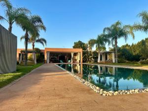 a swimming pool in front of a house with palm trees at Villa Serenity Marrakech in Châba