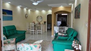 a living room with green couches and a kitchen at Casa de praia em Peruibe com muito verde! in Peruíbe
