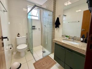 a bathroom with a toilet and a glass shower at Apartamento central com ar condicionado e 3 smart TVs - UFV a 1km in Viçosa