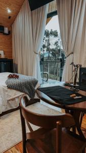 a bedroom with a table and a bed and a window at Cabana Verona, Villa Itália- Urubici in Urubici