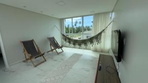 a living room with a hammock and a television at Casa Estrela do Mar in Maragogi