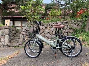ein Fahrrad ist vor einer Steinmauer geparkt in der Unterkunft Gateway to Hakuba & Snow Monkey - Historic 200yo Home in Nagano