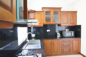 a kitchen with wooden cabinets and a sink and a microwave at Modern 3 BR Apt in Dehiwala +2 photos
