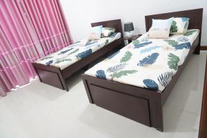 two twin beds in a bedroom with pink curtains at Modern 3 BR Apt in Dehiwala
