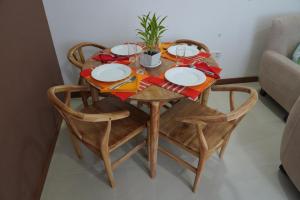 a wooden table with chairs and plates and a plant on it at Modern 3 BR Apt in Dehiwala