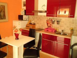 a kitchen with red cabinets and a white table with chairs at Charming Apartments Kestenovi Dvori- 2 Bedroom A1 in Opric +8 photos