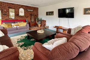 Una sala de estar con sofás y un televisor de pantalla plana. en Location Location 400m From Beach and Town Centre, en Whitianga