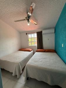 two beds in a room with a ceiling fan at Casa Morroken Ixtapa con Alberca in Ixtapa +13 photos