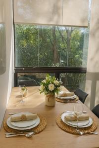 une table en bois avec des assiettes et des verres ainsi qu'une fenêtre dans l'établissement Lourenço House, à Barueri