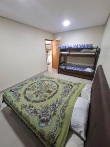 a bedroom with a bed with a green blanket on it at Quinta in Itauguá