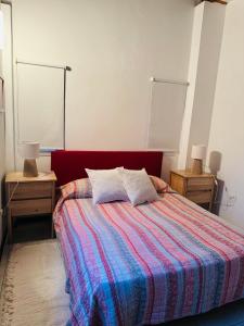 a bedroom with a bed with a colorful blanket and two tables at Departamento tres ambientes Pinamar Centro in Pinamar
