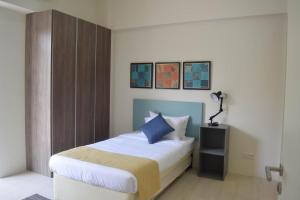 a bedroom with a bed with white sheets and blue pillows at By The Sea - SDBMS in Batu Ferringhi +2 photos