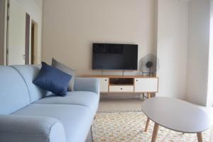 a living room with a blue couch and a tv at By The Sea - SDBMS in Batu Ferringhi