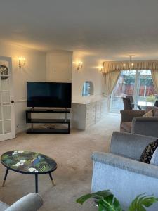 a living room with a tv and a couch and a table at Stylish 3 Bed House Located in the Heart of Chigwell in Fairlop Station