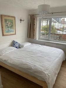 a bed with white sheets and a window in a bedroom at Stylish 3 Bed House Located in the Heart of Chigwell in Fairlop Station