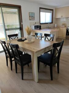 einen Holztisch mit schwarzen Stühlen und eine Küche in der Unterkunft Oleander Cottage in Lake Albert