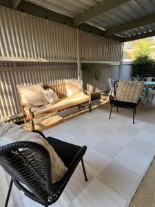 eine Terrasse mit 2 Stühlen, einer Bank und einem Tisch in der Unterkunft Oleander Cottage in Lake Albert