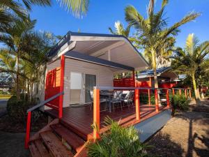 a house with a deck with a table and chairs at Lakeside Forster Holiday Park in Forster