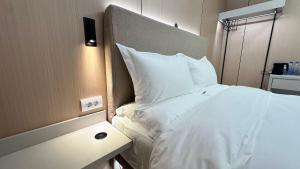 a bed with white sheets and pillows in a room at Kimmiy in Beograd