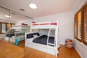 a bedroom with two bunk beds and a table at Anchor Beachfront - Pet Friendly on the Beach in Frankston