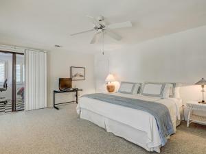 a white bedroom with a bed and a ceiling fan at Coops Retreat in Tybee Island +42 photos