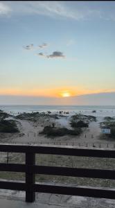 a view of a beach at sunset with a bench at Kitnet Pontal Beach in Arraial do Cabo