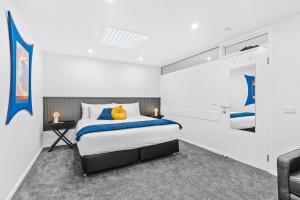 a white bedroom with a bed and a chair at The Prescription Pad - Group Getaway for Families in Port Sorell