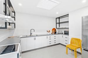 a kitchen with white cabinets and a yellow chair at The Prescription Pad - Group Getaway for Families in Port Sorell
