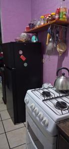 a kitchen with a white stove and a black refrigerator at Cativa CozyHomestay in Hermosillo
