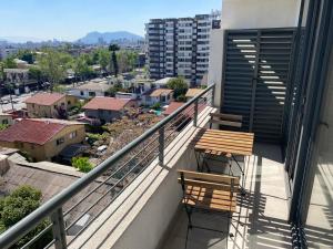 a balcony with two chairs and a view of a city at Nuñoa a un paso de todo lo que necesitas in Santiago