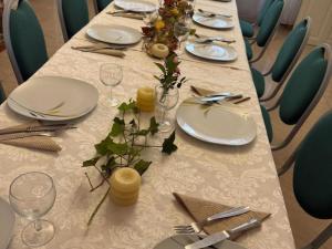 un lungo tavolo con piatti e bicchieri bianchi e fiori sopra di Maison de maître XIXe avec piscine, étang à proximité et équipements modernes - FR-1-489-505 a Gipcy