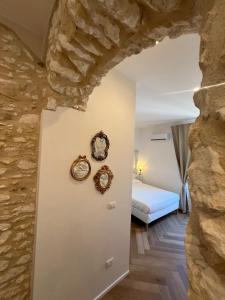 a bedroom with a stone wall with clocks on the wall at Cuore Antico - Il Monastero Sul Mare in Vieste +4 photos