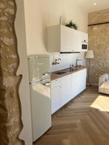 a kitchen with white cabinets and a refrigerator at Cuore Antico - Il Monastero Sul Mare in Vieste