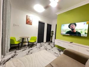 a living room with a flat screen tv on a green wall at Cozy Lovely 1 bedroom apartment in Tema