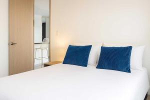 a white bed with two blue pillows on it at Apartaestudio cerca centros comerciales -Refugio romantico in Ibagué +9 photos