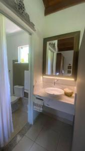 Un baño con lavabo, espejo e inodoro. en Cabana graciosa e aconchegante, en Jaguariúna