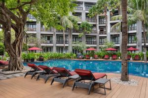 a hotel swimming pool with chairs and a building at Pullman Bali Legian Beach in Legian